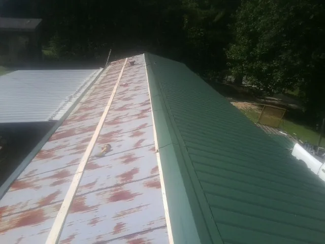 Old rusted panels beside newly installed green metal roofing — Wind Damage Roof Repair by Roofing Brothers in Shreve