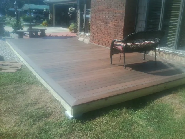 New wood deck and wicker chair beside a brick house in Shreve