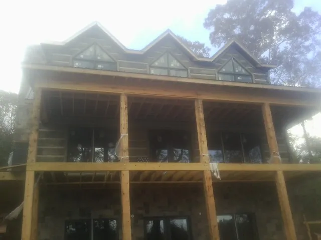 Dormers and porch framing on a large log home under construction — Roof Coating work by our crew in Shreve