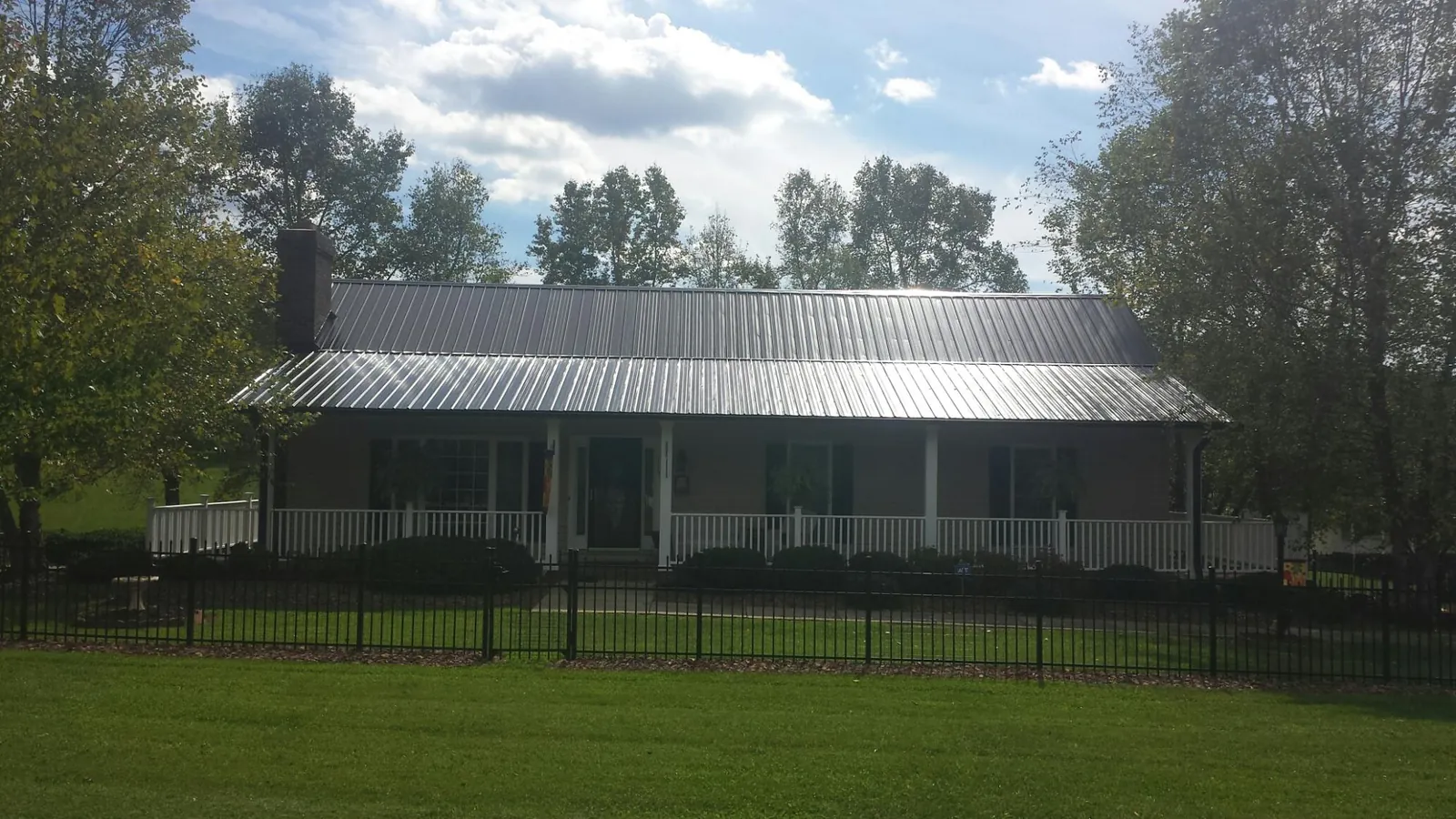 Gray metal roof on a brick ranch with a full width front porch — Gutter Guard Installation work by our crew in Shreve