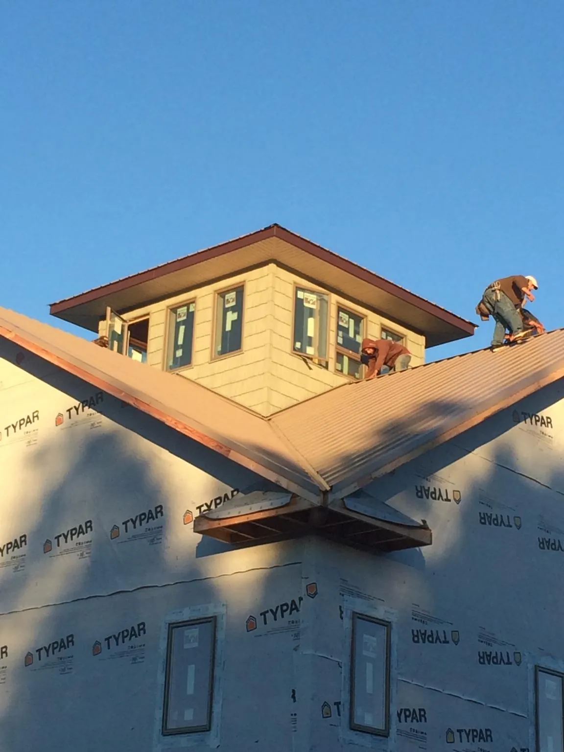 Roofers working around a rooftop cupola on a new metal roof at sunset — Roof Waterproofing in Shreve by Roofing Brothers
